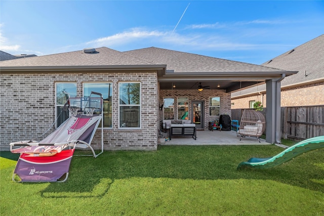 rear view of property featuring brick siding, a shingled roof, a lawn, a patio area, and fence