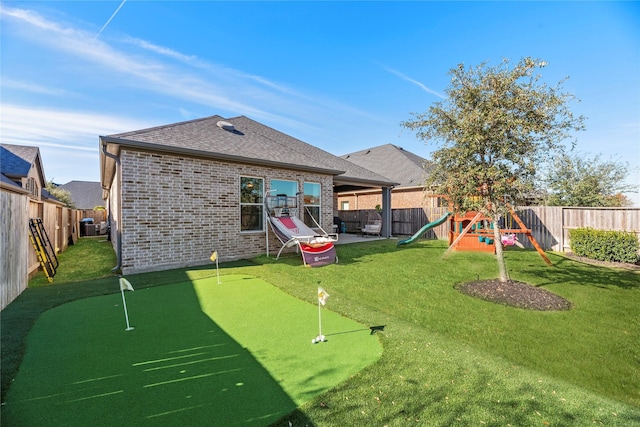 rear view of house featuring a patio area, a yard, brick siding, and a playground