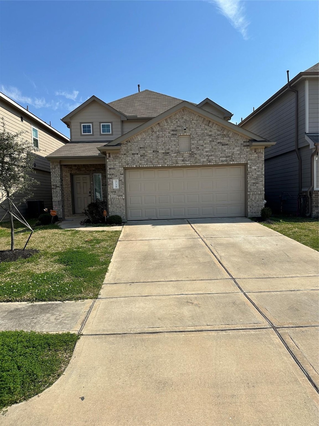 view of front facade with a front yard, driveway, a shingled roof, a garage, and brick siding