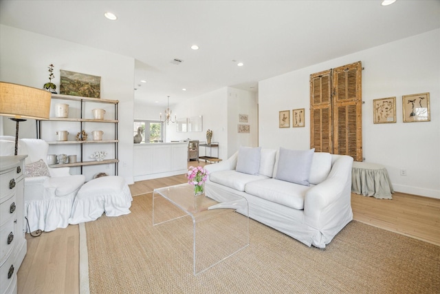 living room with visible vents, baseboards, light wood-style floors, a notable chandelier, and recessed lighting