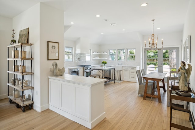 kitchen featuring light wood-type flooring, a healthy amount of sunlight, and high end stainless steel range oven