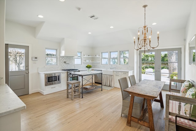 dining space featuring french doors, plenty of natural light, and light wood-style flooring