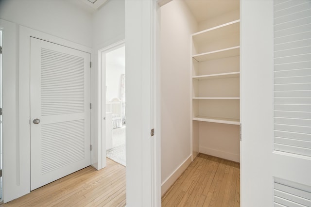 hall with light wood-style floors and baseboards