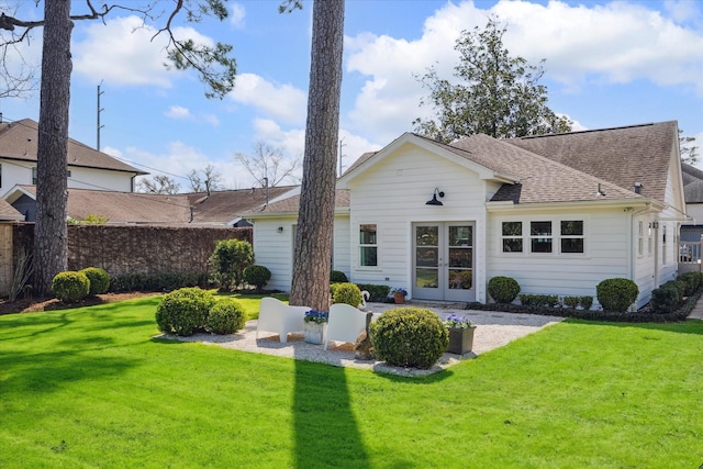 back of house featuring a shingled roof, french doors, a yard, and fence