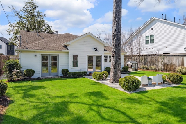 back of house featuring french doors, roof with shingles, a lawn, a patio area, and fence