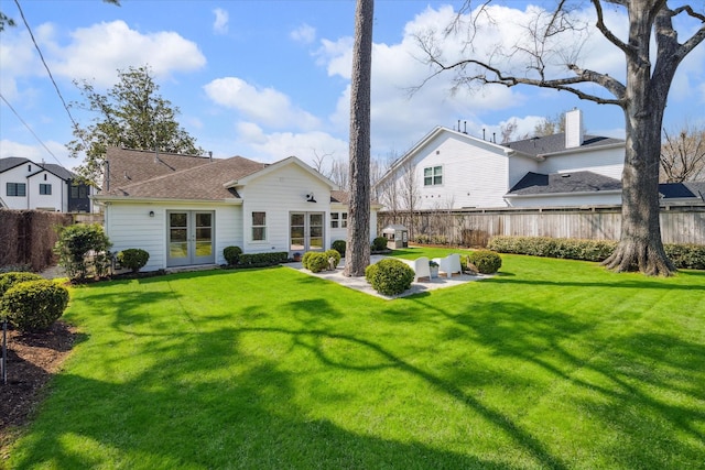 back of property with a yard, a fenced backyard, a patio area, and french doors