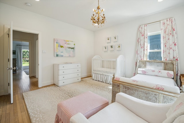 bedroom with baseboards, hardwood / wood-style flooring, and an inviting chandelier