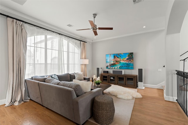 living room featuring crown molding, visible vents, a ceiling fan, light wood-type flooring, and baseboards