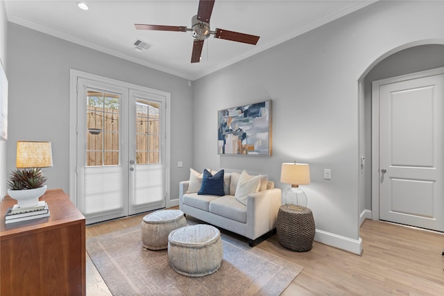 living area with light wood-type flooring, baseboards, visible vents, and crown molding