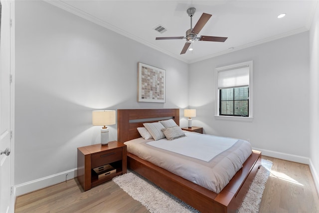 bedroom with visible vents, crown molding, baseboards, and wood finished floors