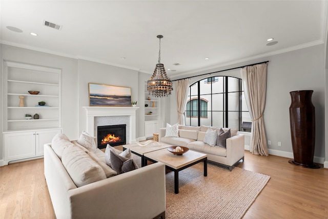 living room with light wood-style flooring, built in shelves, visible vents, and ornamental molding