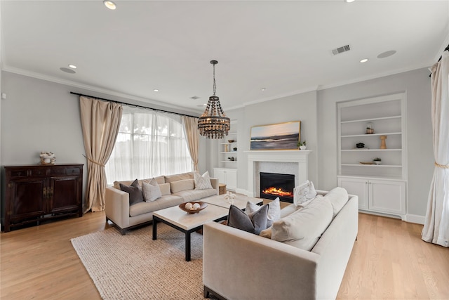 living room with light wood-style floors, built in shelves, visible vents, and a glass covered fireplace