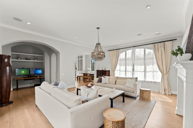 living area featuring built in shelves, baseboards, ornamental molding, and light wood finished floors