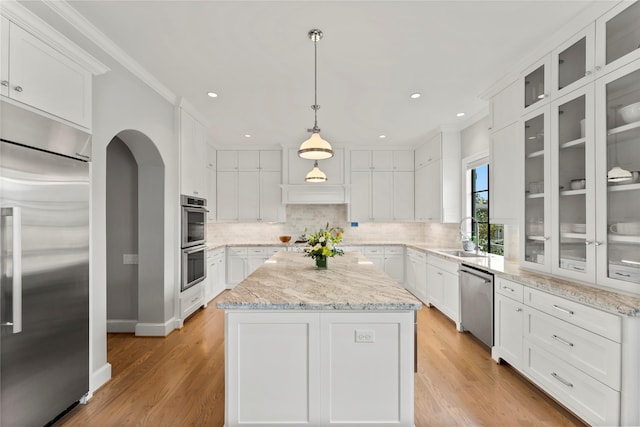 kitchen featuring white cabinets, decorative backsplash, a kitchen island, stainless steel appliances, and a sink