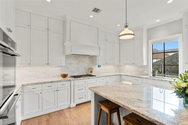 kitchen featuring stainless steel appliances, a sink, white cabinetry, visible vents, and decorative backsplash