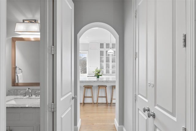 interior space with arched walkways, a sink, and light wood-style flooring