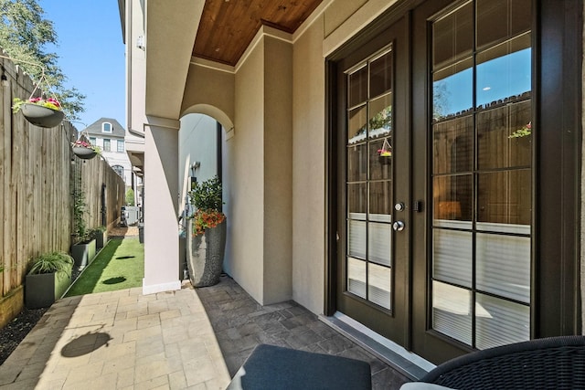 doorway to property featuring french doors, a patio area, fence, and stucco siding