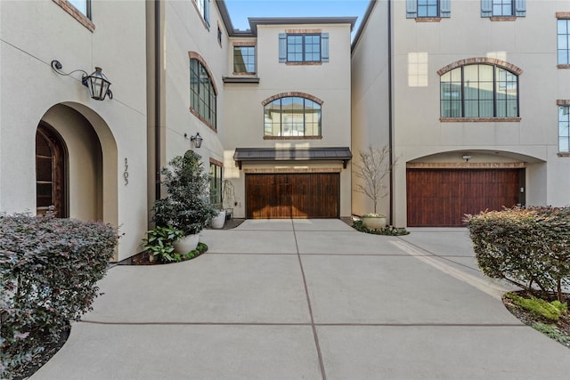 view of front of home with an attached garage, concrete driveway, and stucco siding