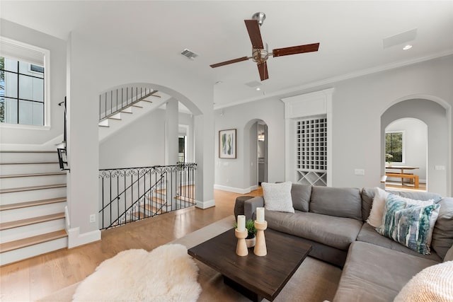 living room with a healthy amount of sunlight, visible vents, arched walkways, and wood finished floors