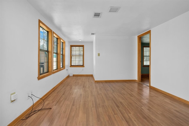 empty room with baseboards, visible vents, and wood finished floors