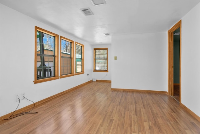 empty room with light wood-type flooring, visible vents, and baseboards