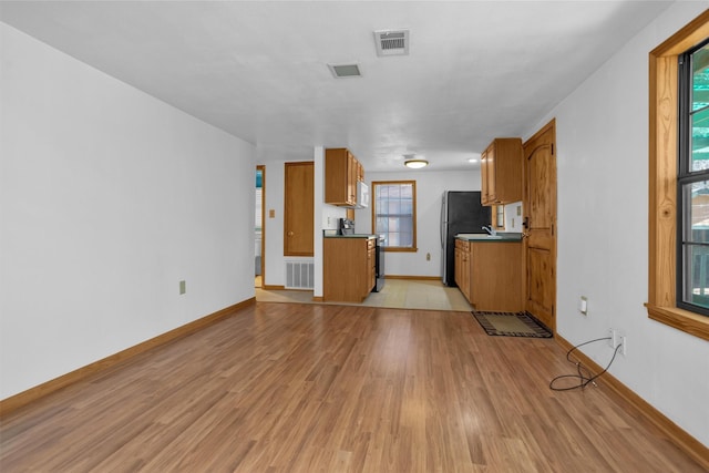 unfurnished living room with plenty of natural light, visible vents, and light wood-style floors