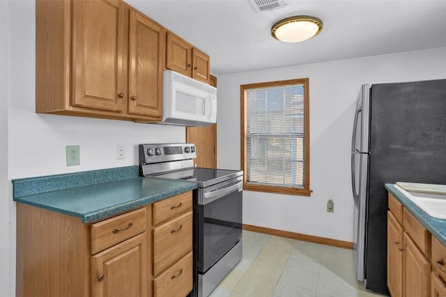 kitchen with brown cabinets, stainless steel appliances, dark countertops, visible vents, and baseboards