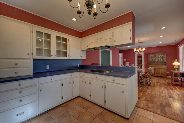 kitchen with a chandelier, a peninsula, black cooktop, white cabinets, and dark countertops