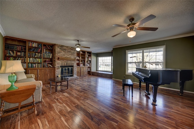 sitting room featuring baseboards, ornamental molding, wood finished floors, a textured ceiling, and a fireplace