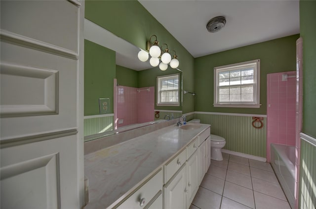 full bathroom with wainscoting, toilet, tile patterned flooring, a washtub, and vanity