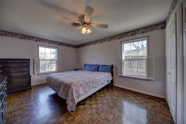 bedroom featuring ceiling fan, multiple windows, and baseboards