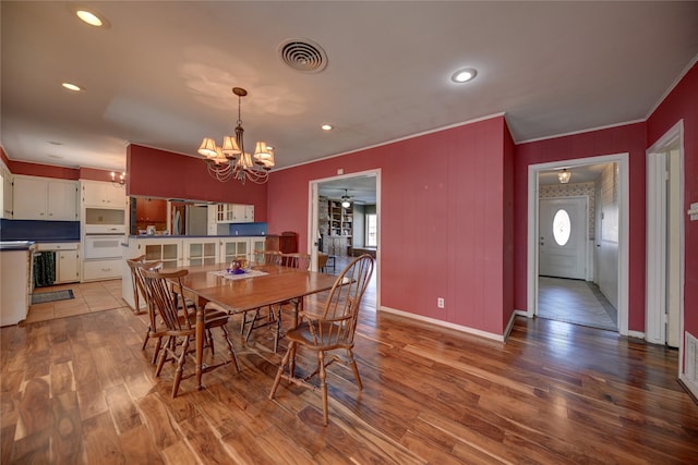 dining room featuring baseboards, wood finished floors, visible vents, and crown molding