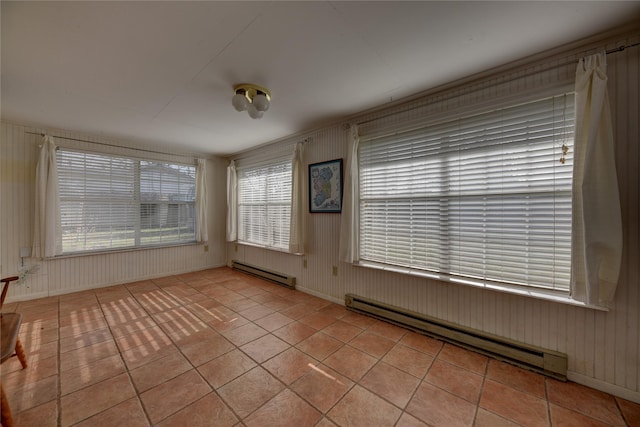 empty room with light tile patterned floors, a baseboard radiator, and baseboards