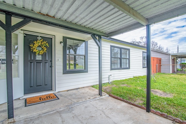 doorway to property featuring fence and a lawn