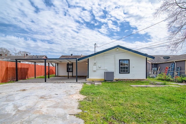 rear view of property with central AC, fence, driveway, a lawn, and a carport