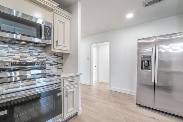 kitchen featuring stainless steel appliances, visible vents, light countertops, light wood finished floors, and tasteful backsplash