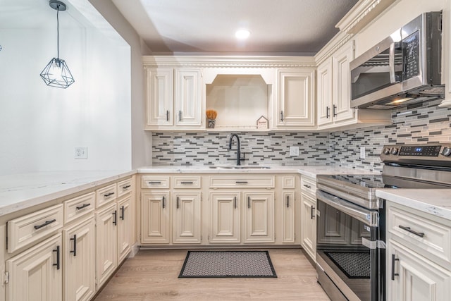 kitchen with stainless steel appliances, a sink, light wood-style floors, tasteful backsplash, and decorative light fixtures