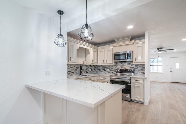 kitchen with stainless steel appliances, light wood-style floors, a sink, and backsplash