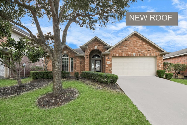 view of front facade with a garage, a front yard, brick siding, and driveway