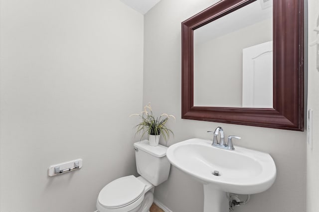 half bathroom featuring visible vents, a sink, toilet, and baseboards