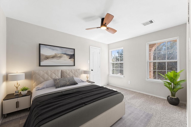 carpeted bedroom with a ceiling fan, visible vents, and baseboards