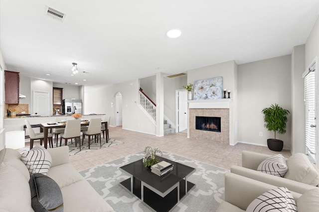 living room featuring visible vents, arched walkways, stairs, a fireplace, and recessed lighting