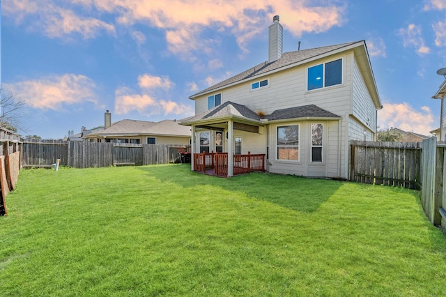 back of property at dusk featuring a fenced backyard, a chimney, and a lawn