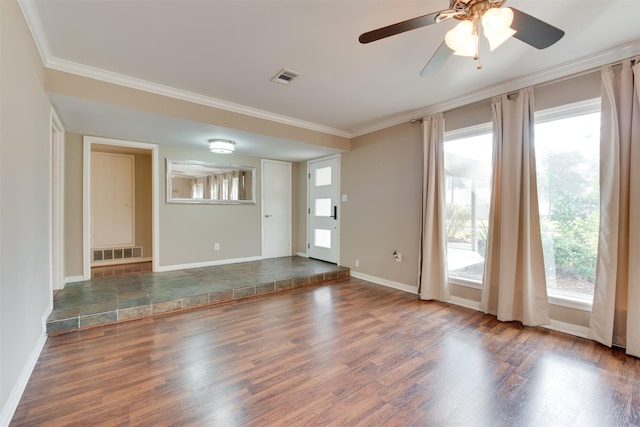 unfurnished room featuring baseboards, visible vents, crown molding, and wood finished floors