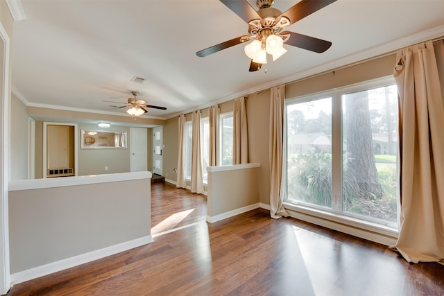 spare room featuring visible vents, crown molding, baseboards, and wood finished floors