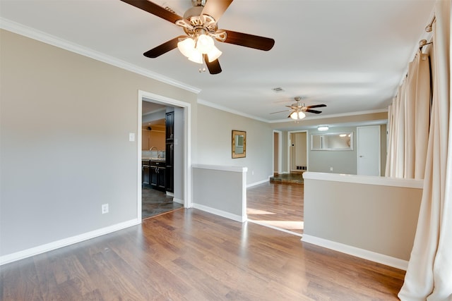 unfurnished room featuring baseboards, wood finished floors, visible vents, and crown molding