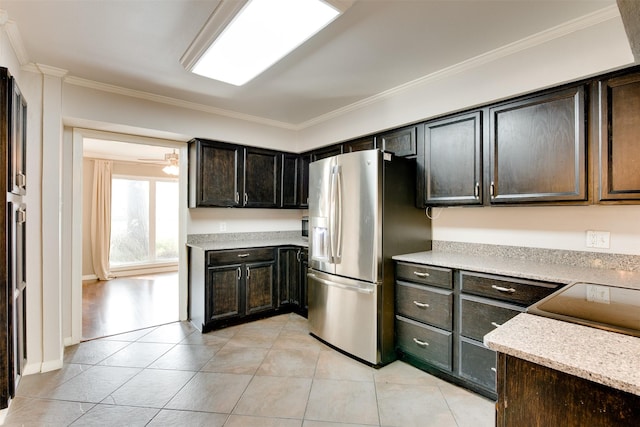 kitchen featuring light tile patterned floors, dark brown cabinetry, a ceiling fan, stainless steel fridge, and crown molding