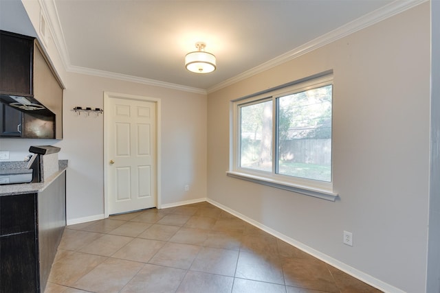 unfurnished dining area featuring light tile patterned flooring, crown molding, and baseboards