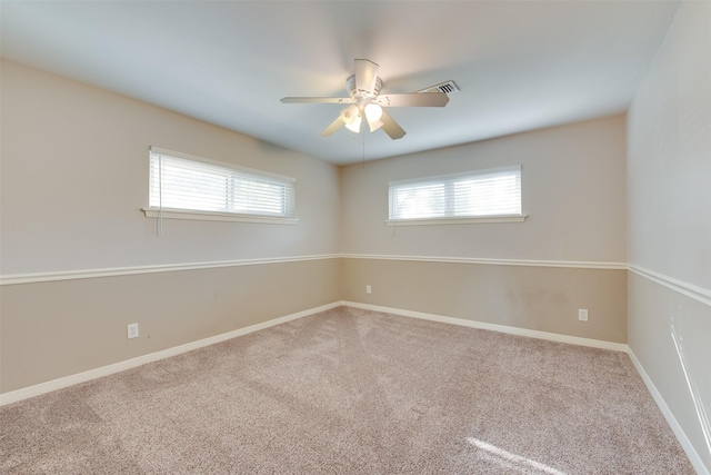 empty room with ceiling fan, visible vents, baseboards, and carpet flooring