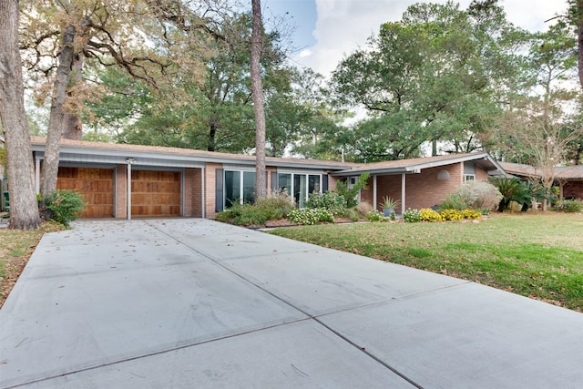 view of front of house with a garage, a front yard, brick siding, and driveway